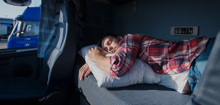 Truck driver resting in a sleeper berth while checking ELD hours
