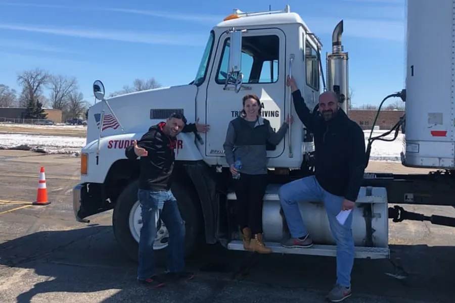 Young truck driving student standing beside a CDL training truck
