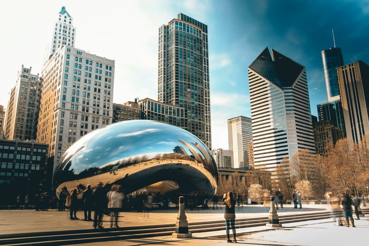 The Cloud Gate sculpture reflecting Chicago skyscrapers and a blue sky on a clear day in Millennium Park